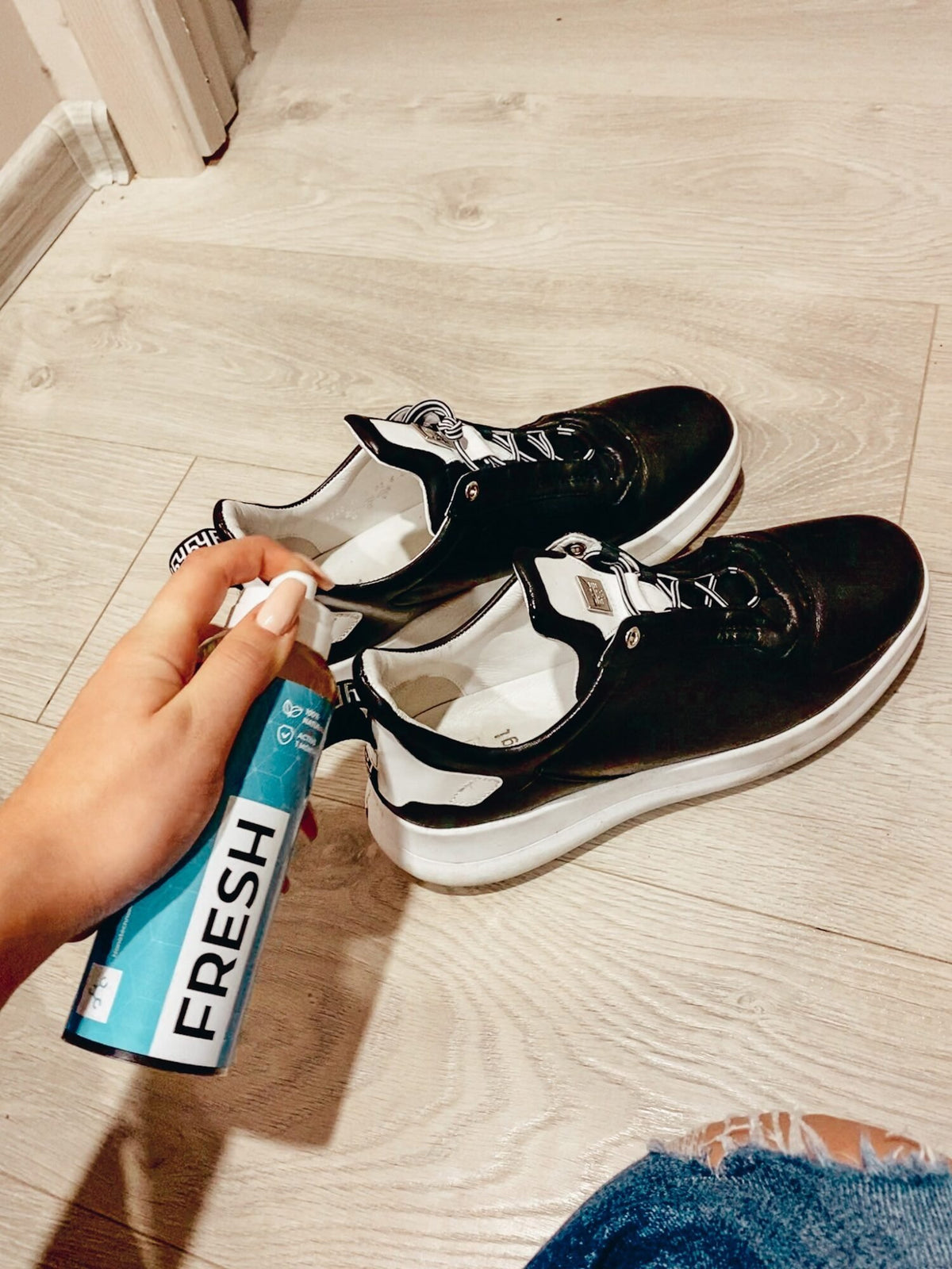 2. GoGoNano shoe freshener being sprayed on black sneakers, showcasing odor-neutralizing action