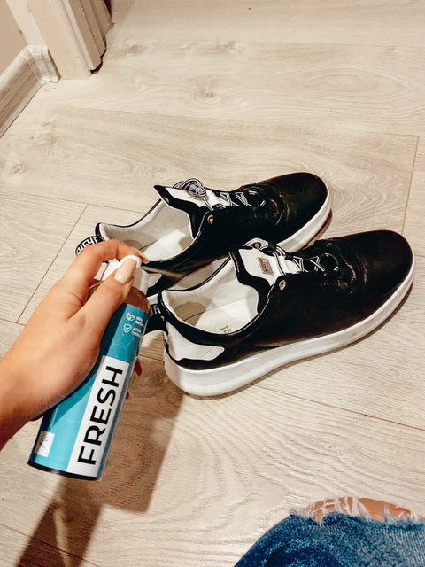 2. GoGoNano shoe freshener being sprayed on black sneakers, showcasing odor-neutralizing action