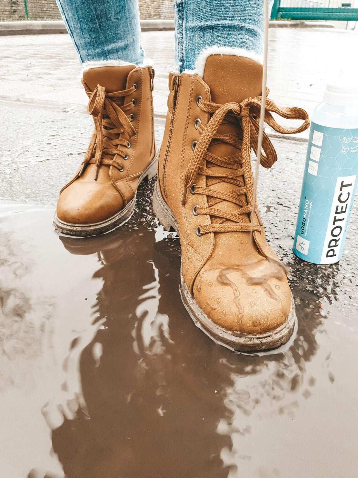 1. Person wearing brown boots standing in puddle with GoGoNano Protect spray bottle nearby, showcasing water-repellent effect
