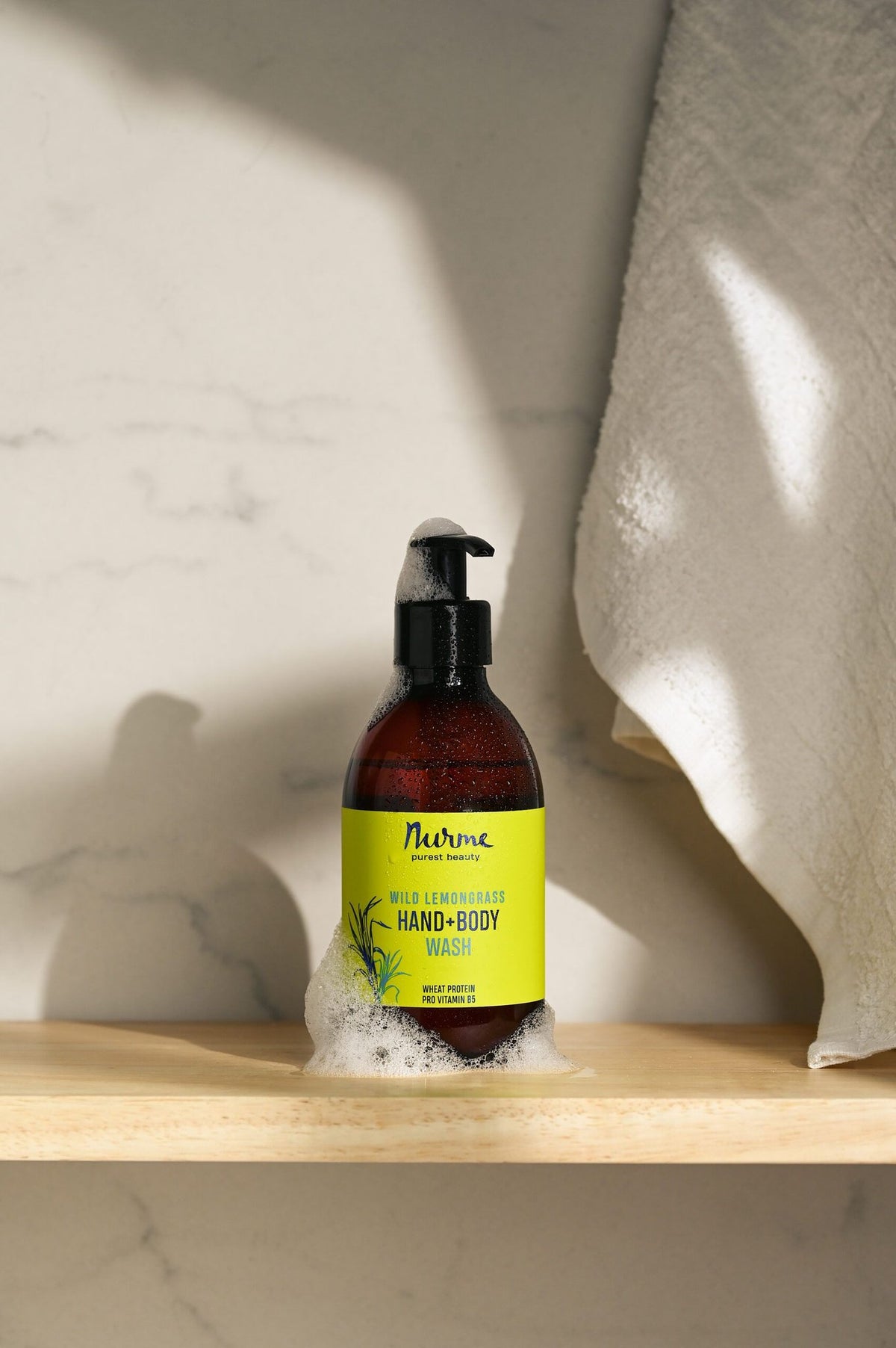 6. Nurme Wild Lemongrass hand and body wash on shelf with foam, highlighting product use