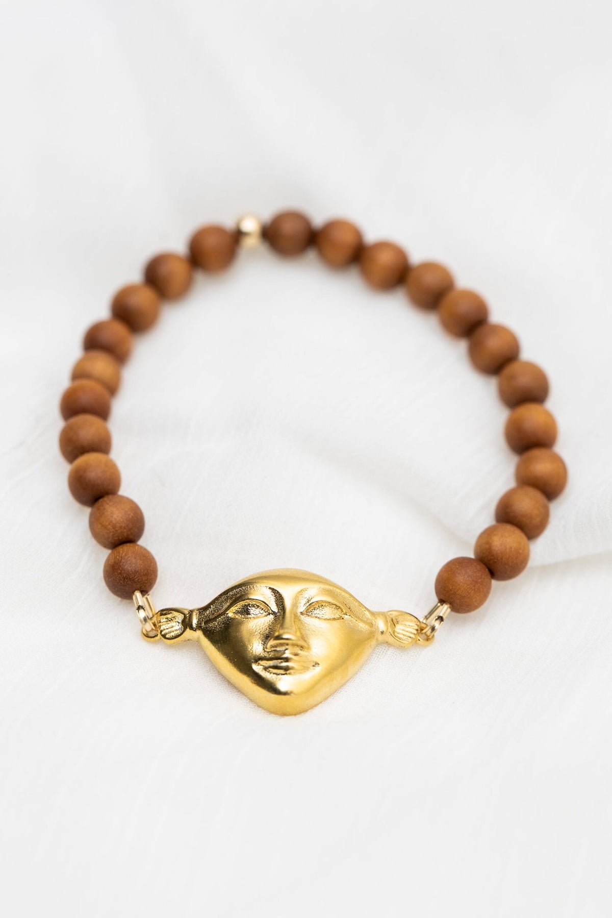 3. Hathor Harmony Bracelet in sandalwood with gold plated silver face, styled on white fabric