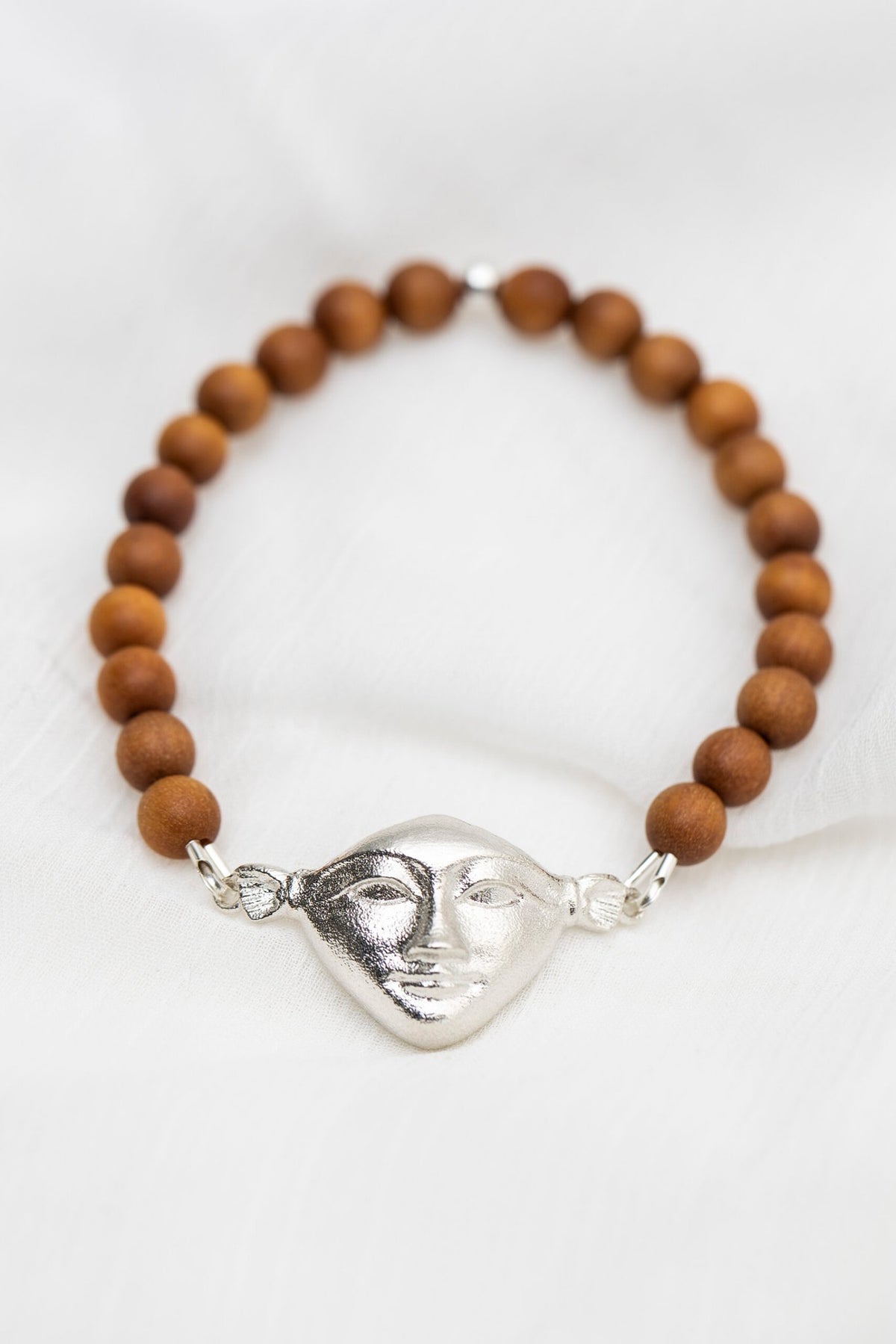 2. Hathor Harmony Bracelet in sandalwood with silver face, styled on white fabric