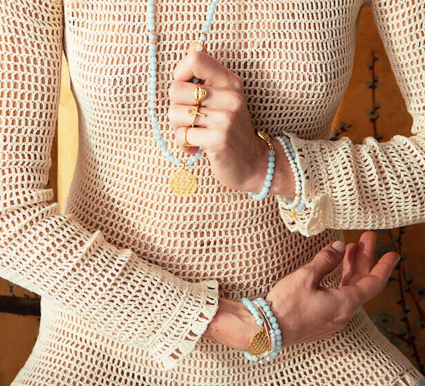 1. Woman wearing Hathor Harmony Ring in gold by New Vintage by Kriss, styled with beaded jewelry in lifestyle setting