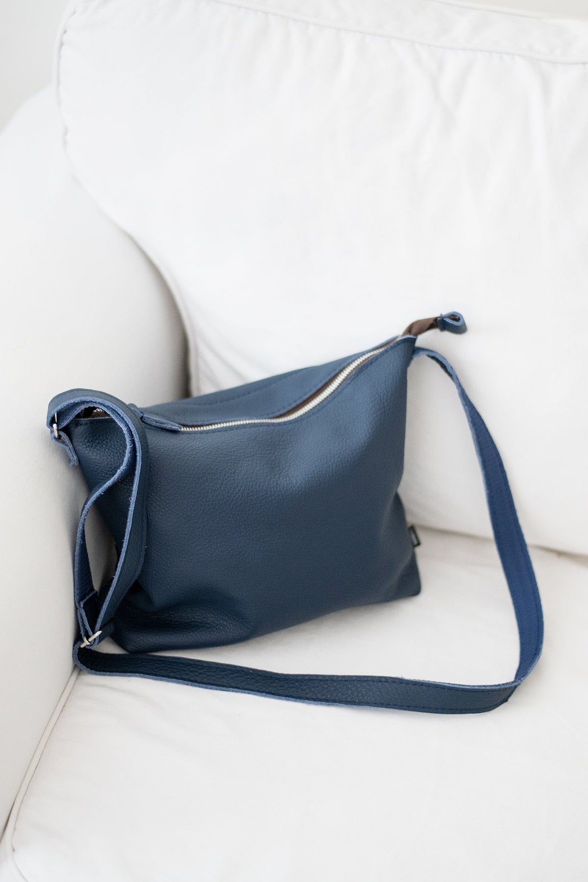 1. Trendbag Anet L shoulder bag in dark blue leather, shown on a white sofa, highlighting eco-friendly design