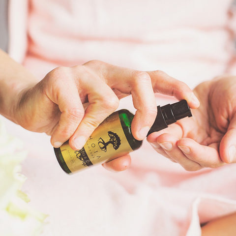 2. Close-up of hands using HOIA homespa Organic Argan Oil bottle, highlighting application