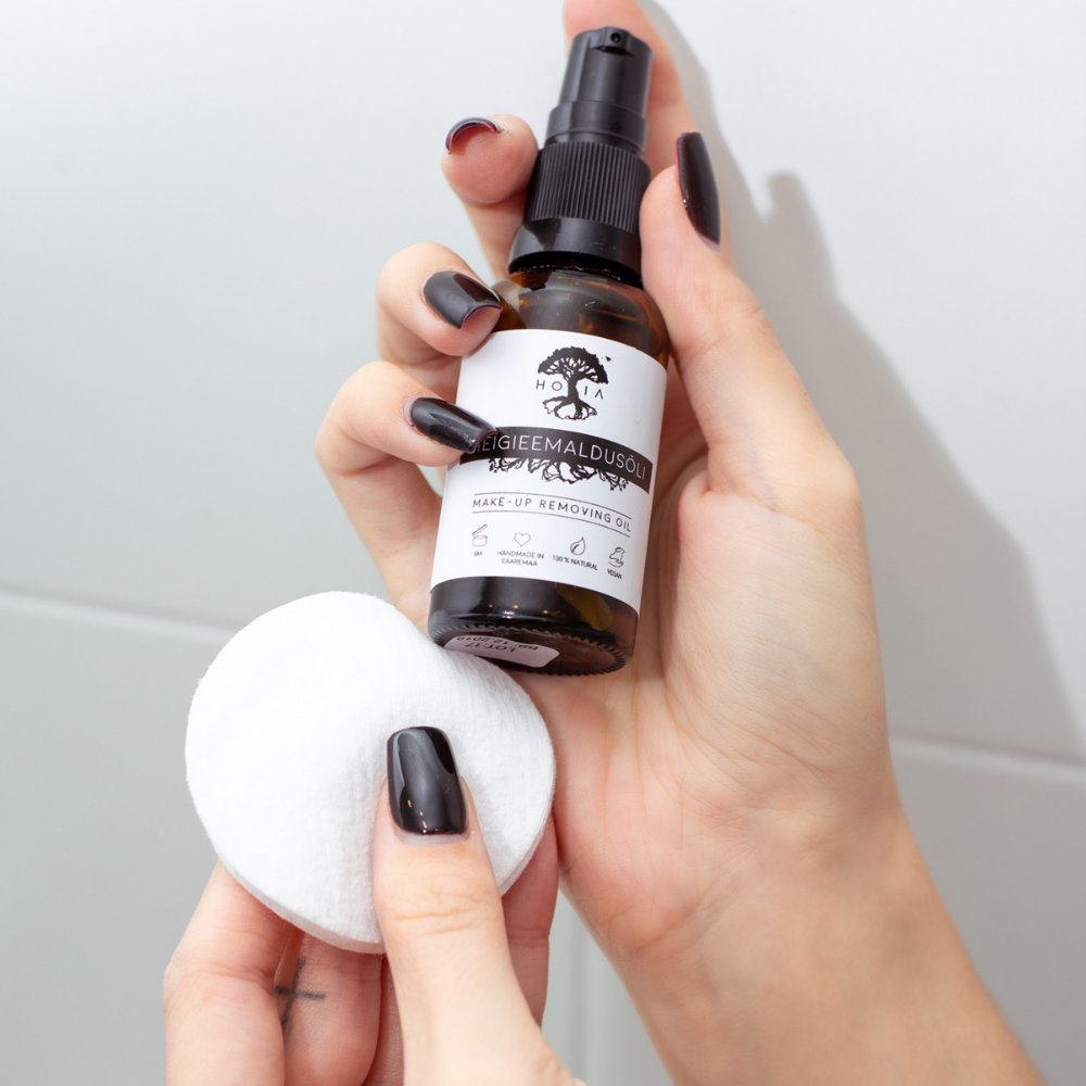 2. Close-up of HOIA homespa organic make-up removing oil bottle held by woman with cotton pad
