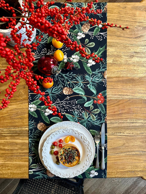 1. Christmas Forest Table Runner by Hortensias Home on wooden dining table with festive decor and plate setting