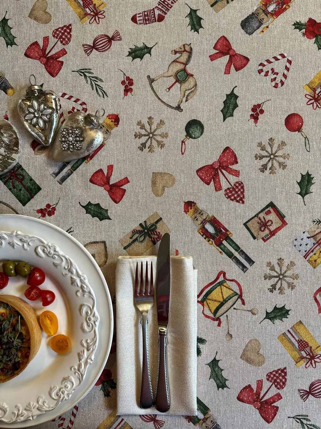 1. Festive Motive Christmas Story tablecloth by Hortensias Home with holiday-themed print, set on dining table with plates and cutlery