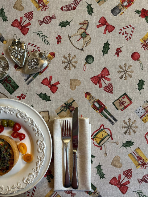 1. Festive Motive Christmas Story tablecloth by Hortensias Home with holiday-themed print, set on dining table with plates and cutlery