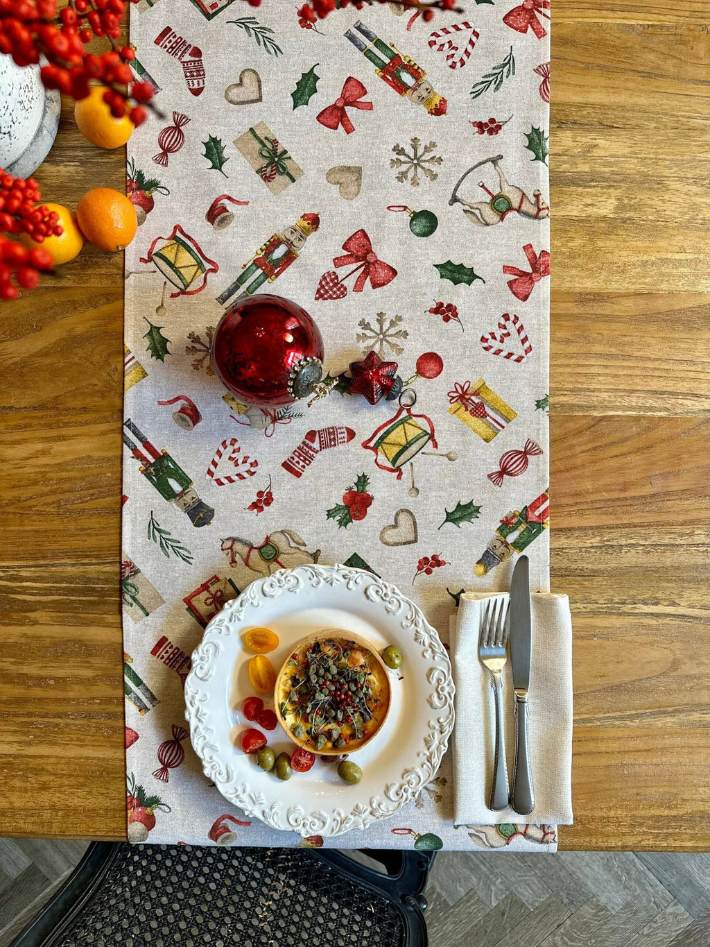 1. Christmas Story Table Runner by Hortensias Home on wooden dining table with festive decorations and a plate setting