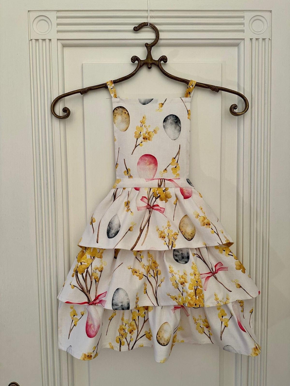 1. Kids Easter Happy apron by Hortensias Home, featuring a charming Easter egg and floral print, shown hanging on a decorative hanger