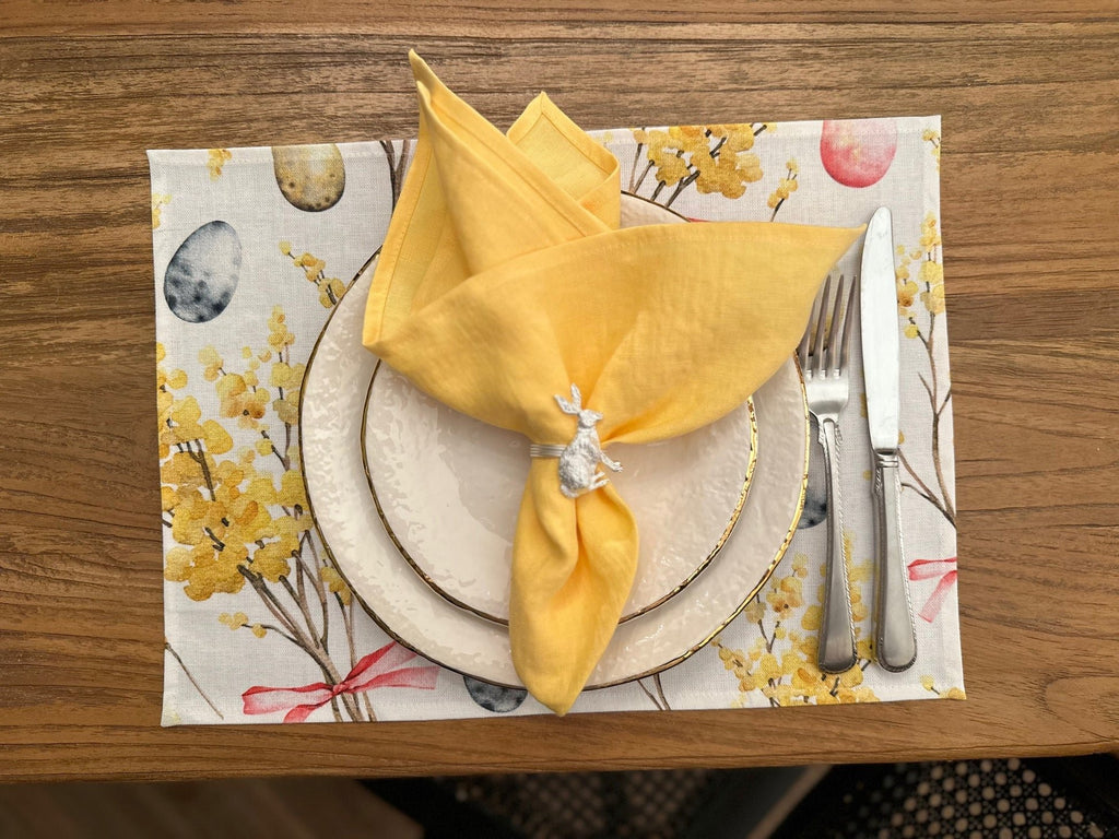 2. Easter Happy table placemat by Hortensias Home with yellow napkin and silverware on wooden table