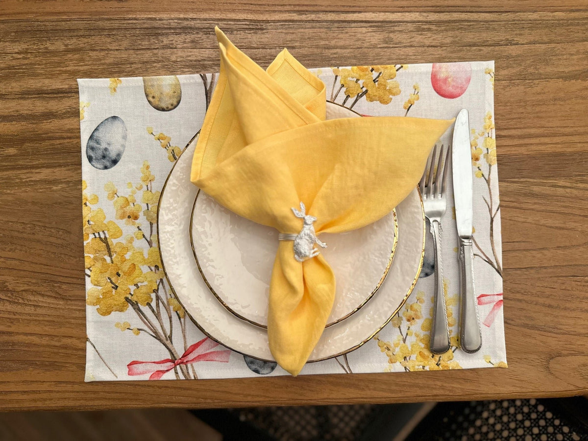 2. Easter Happy table placemat by Hortensias Home with yellow napkin and silverware on wooden table