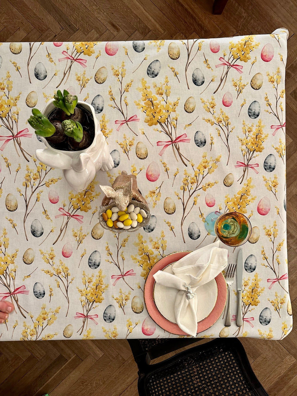 1. Easter-themed rectangular tablecloth by Hortensias Home, featuring festive egg and floral print, styled on a dining table with decorative elements