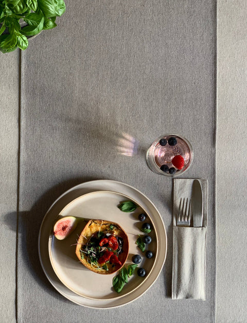 3. Overhead view of Hortensias Home Nord 2 table runner in a dining setting with a plate of food and a drink, highlighting the blue striped design