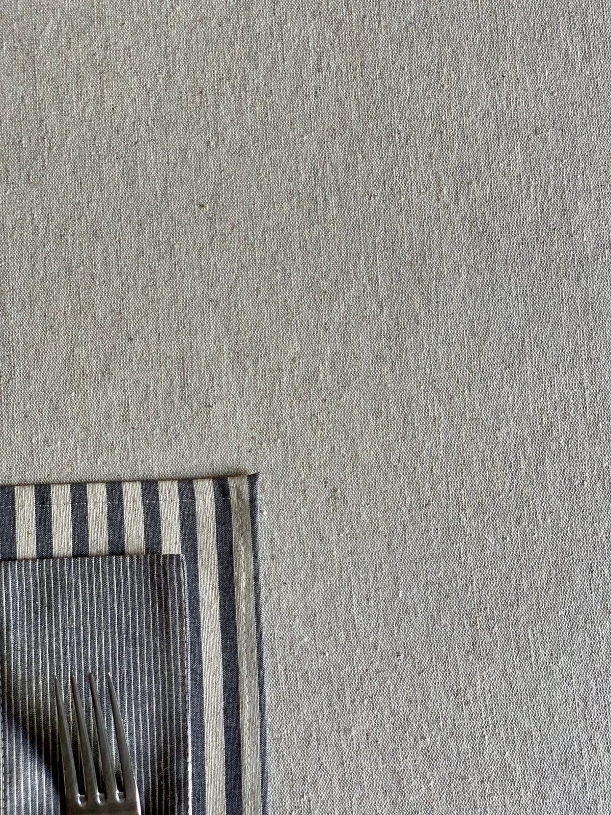 2. Close-up of Hortensias Home Nord 3 tablecloth with striped napkin, highlighting texture and recycled fabric