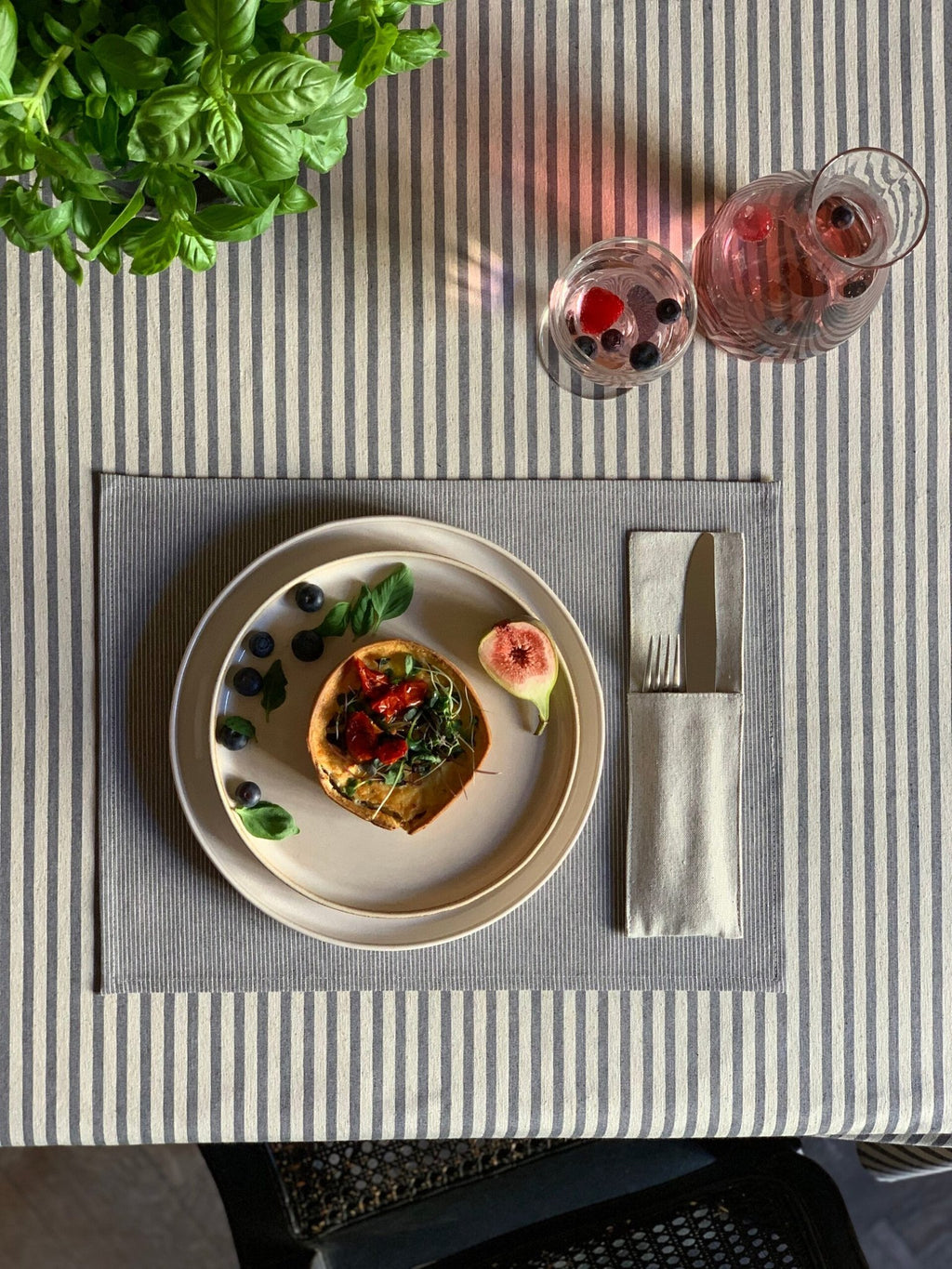 2. Rectangular tablecloth with blue stripes from Nord 1 Collection by Hortensias Home, styled with a meal setting, highlighting sustainable materials