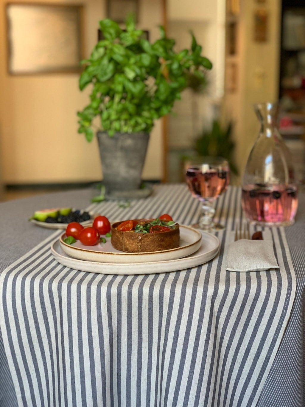 1. Lifestyle image of Nord 1 table runner with blue stripes by Hortensias Home, styled with a meal setting