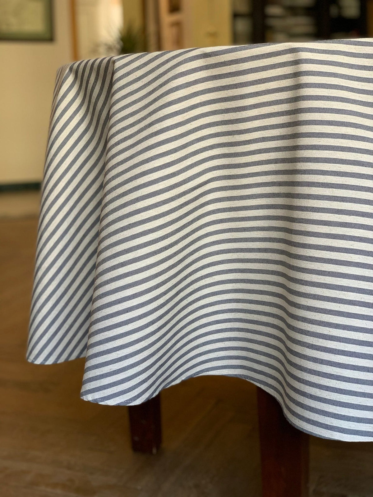 3. Studio shot of Hortensias Home round tablecloth in beige with blue lines, highlighting fabric texture and drape