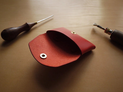 2. Open view of Mirgoods red leather wallet with brass button, displayed with crafting tools
