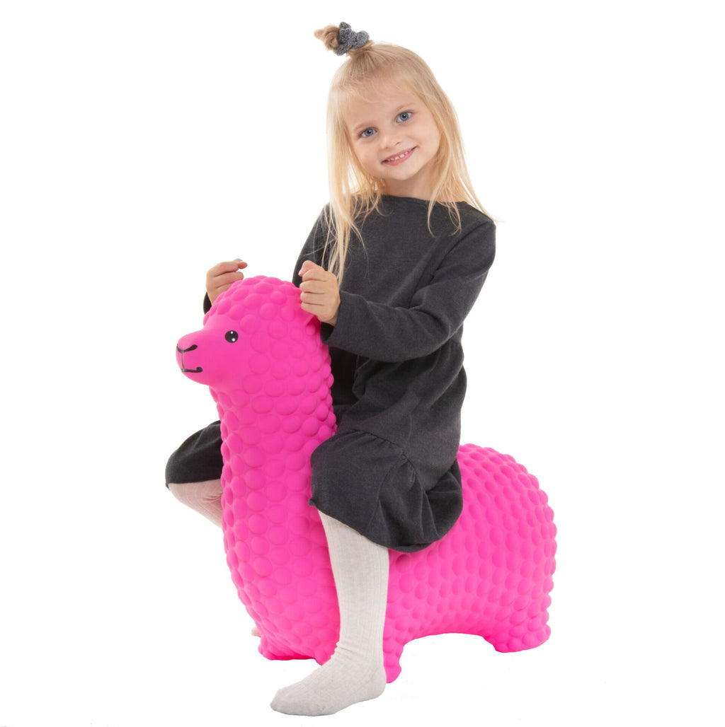 1. Young girl in grey dress sitting on pink alpaca-shaped hopper toy indoors