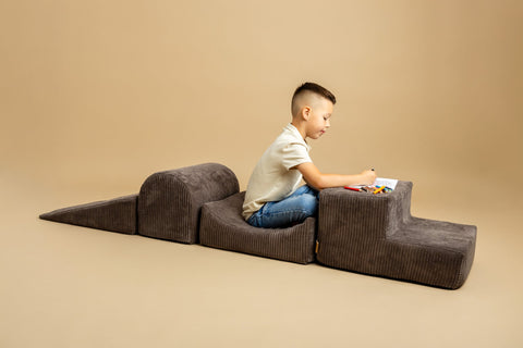 1. Boy sitting on brown velvet corduroy play set drawing with colored pencils on beige background