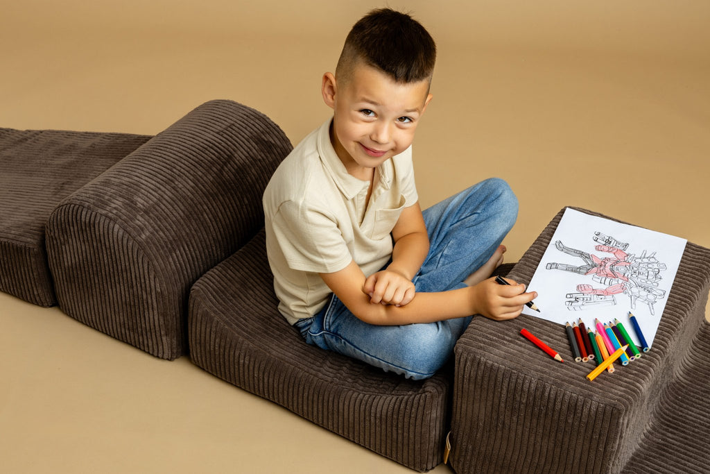 1. Young boy sitting on brown velvet corduroy play set drawing with colored pencils on beige background