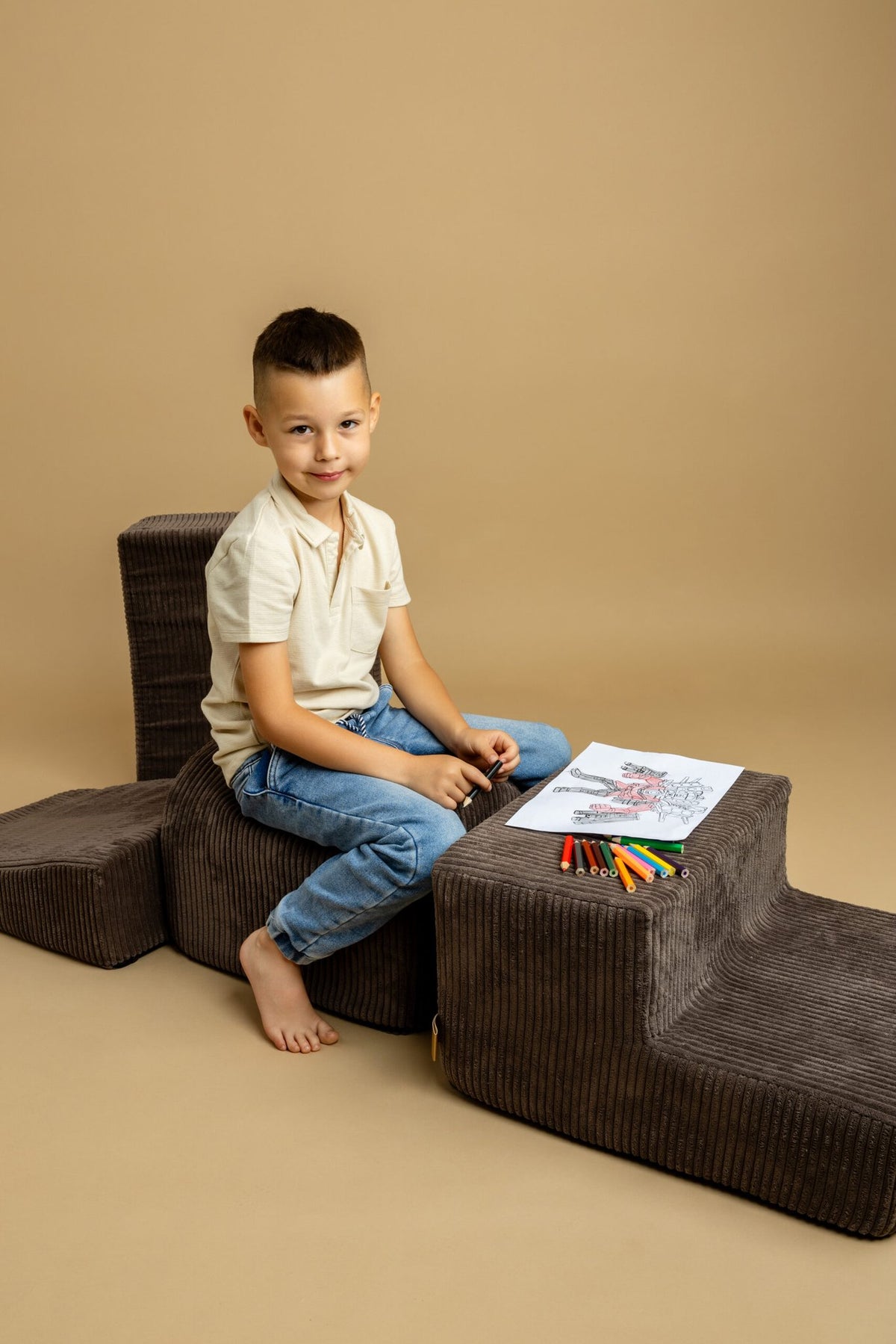 5. Boy playing on brown velvet corduroy play set with crayons and coloring book on beige background