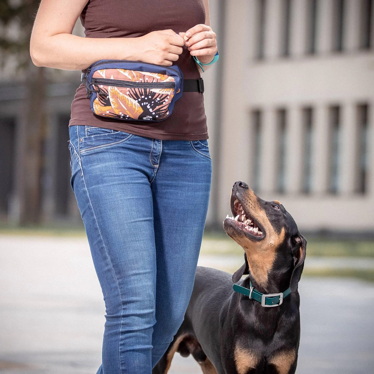 1. Woman wearing Drinbags BLACK HOLE dog treat bag with colorful design, walking dog outdoors