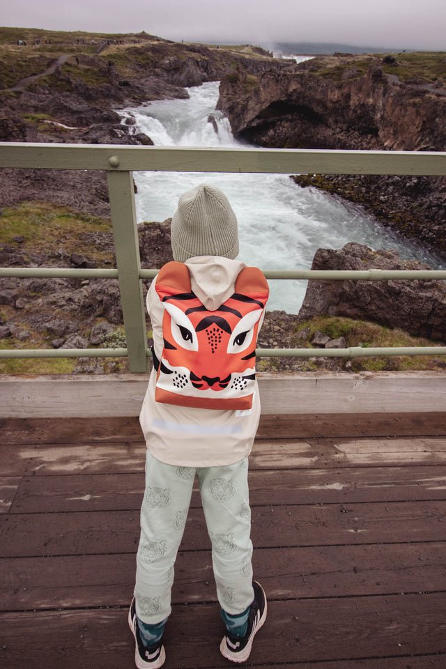 2. Child with Muni Tiger backpack on a bridge, highlighting adventurous spirit and vibrant design