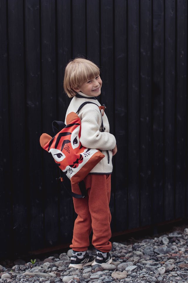 1. Child wearing Muni Tiger backpack outdoors, showcasing playful tiger design and adjustable straps