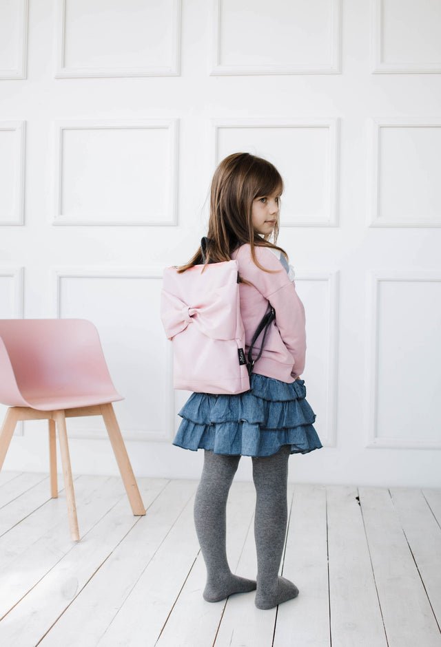 1. Girl wearing Muni kids waterproof pink bow backpack in lifestyle setting
