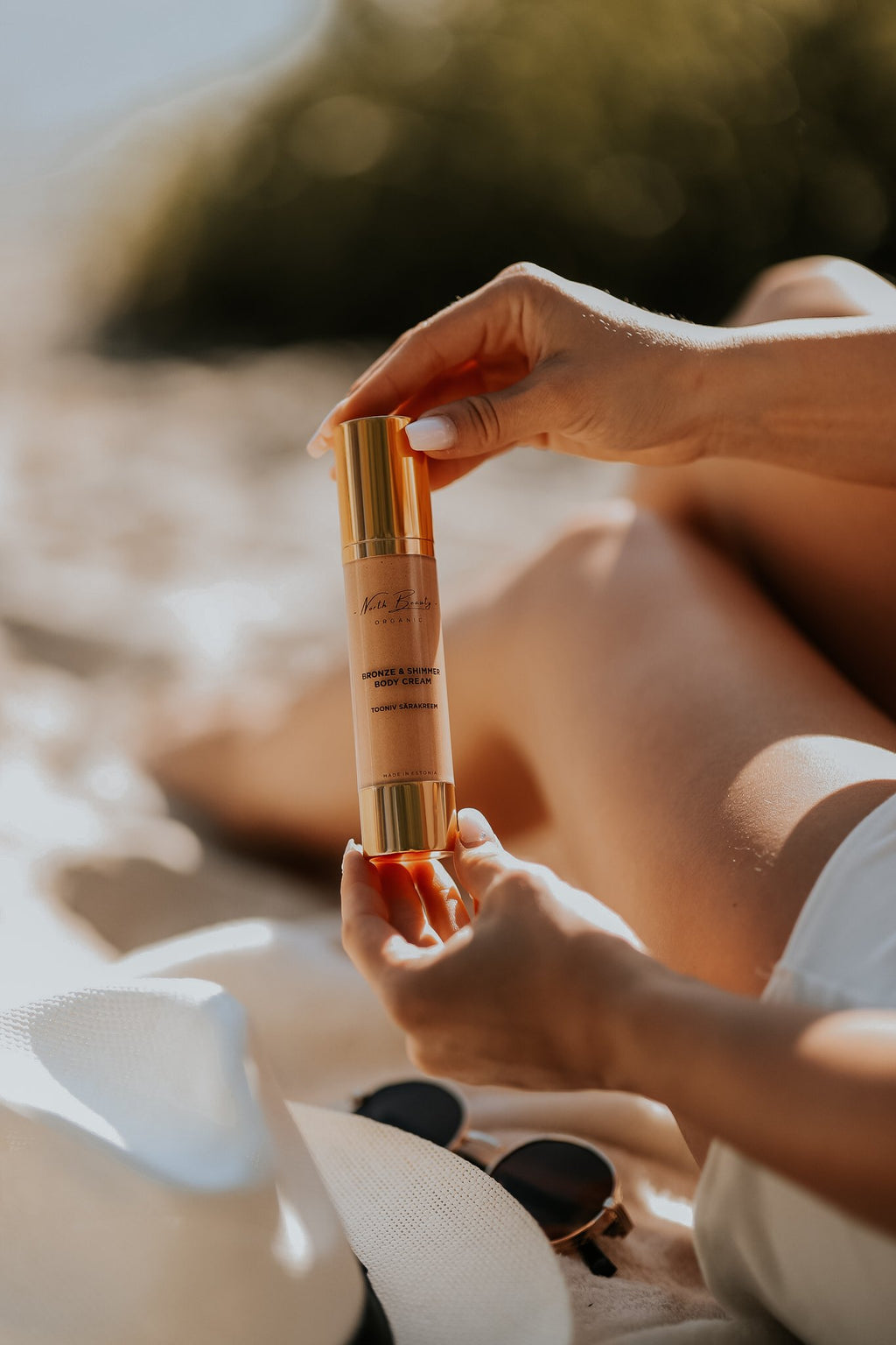 1. Woman holding North Beauty Tinted Glow Cream on beach, showcasing natural glow and hydration