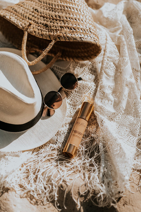 2. North Beauty Tinted Glow Cream with hat and sunglasses on beach, highlighting summer essentials