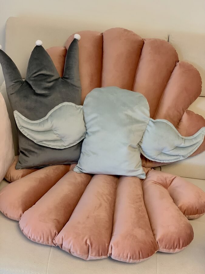 1. Grey decorative cushion with wing design on pink velvet background