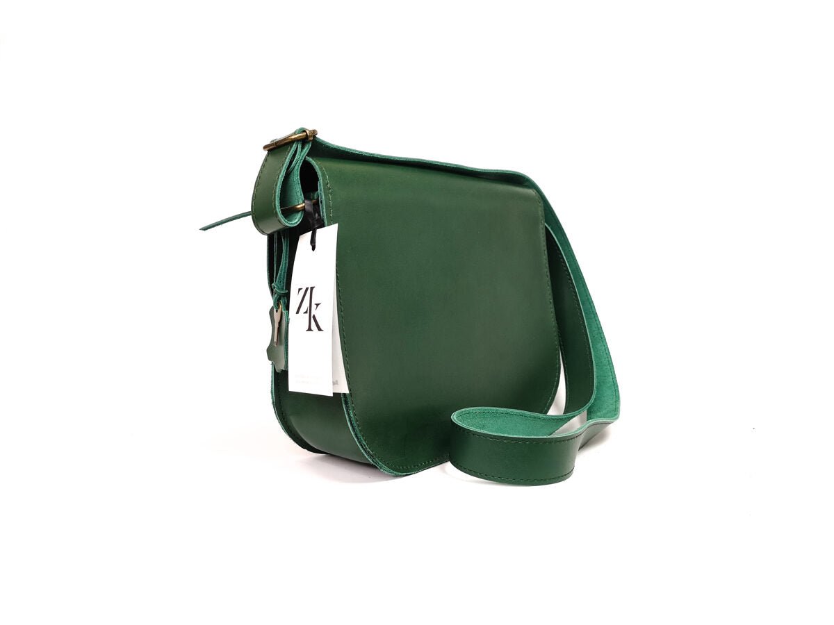 5. Side view of Zelma Kraft green leather saddle bag with adjustable strap and brand tag
