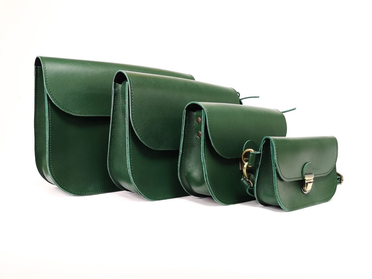 7. Collection of Zelma Kraft green leather saddle bags in various sizes, studio setting