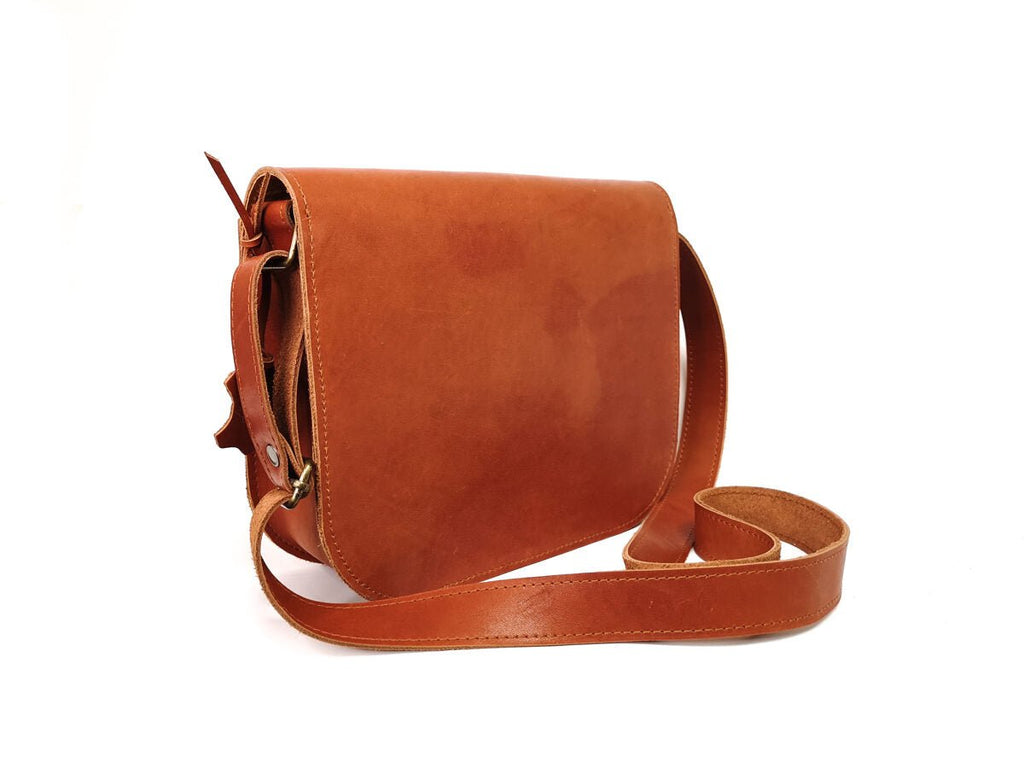 3. Studio shot of Zelma Kraft natural leather saddle bag in light brown, side view highlighting adjustable strap