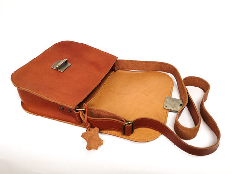 5. Open view of Zelma Kraft natural leather saddle bag in light brown, showing interior and buckle closure