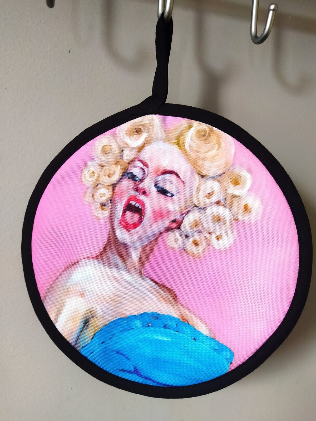 5. Single round pot holder with pop art style painting of a woman with blonde curls and a blue dress hanging on a hook