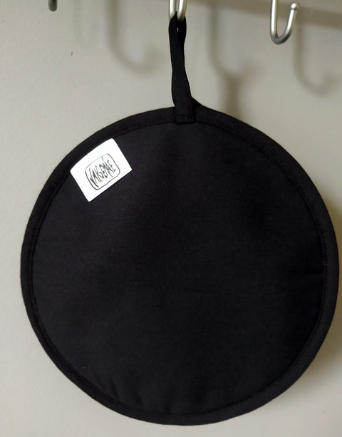 2. Black side of pot holder with Katrin Valgemäe logo, hanging on a hook