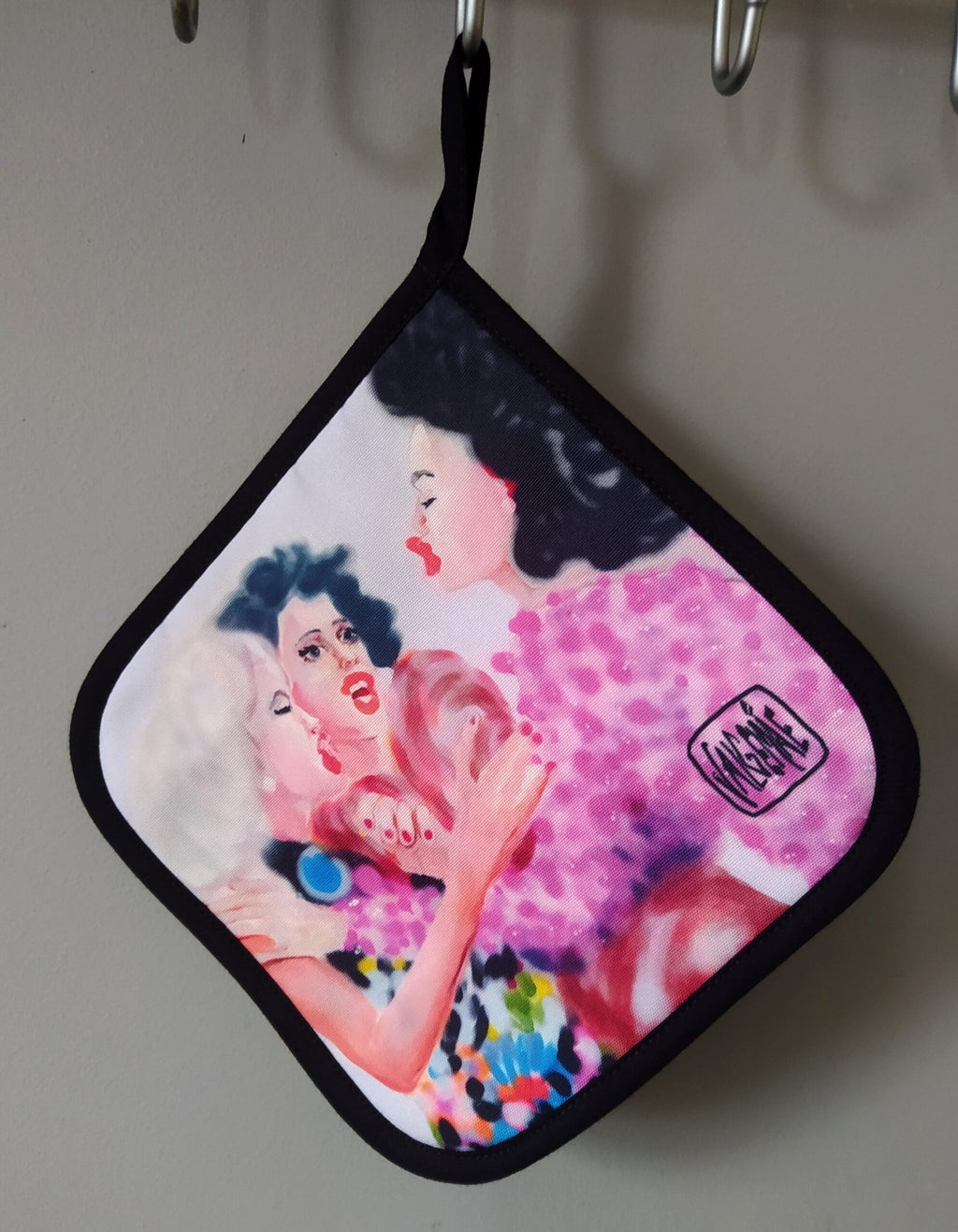 3. Pot holder with 'After Third Prosecco' painting by Katrin Valgemäe, showing three women in colorful attire, hanging on a hook