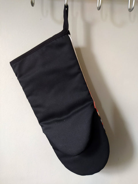 2. Back view of Katrin Valgemäe oven glove in black, hanging on a hook