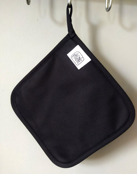 3. Back view of pot holder in black fabric with Katrin Valgemäe logo tag