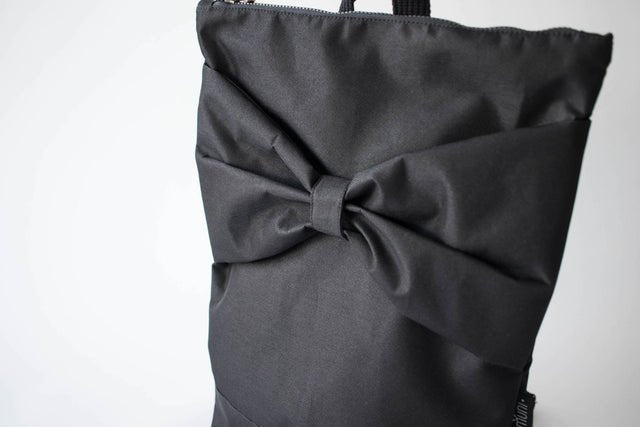 6. Close-up of Muni Black Bow Large waterproof backpack, highlighting bow detail and black polyester fabric