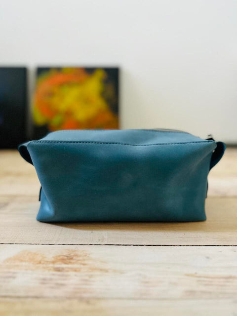 3. Studio shot of eleriinseim leather cosmetic bag in Atlantico color on wooden surface
