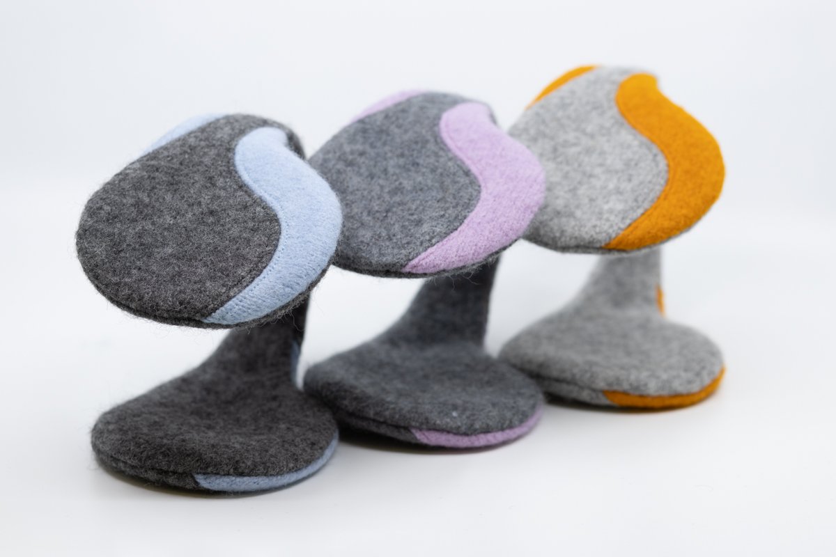 3. Collection of HERTTA felted wool earmuffs in various colors, including light grey and curcuma, displayed in studio