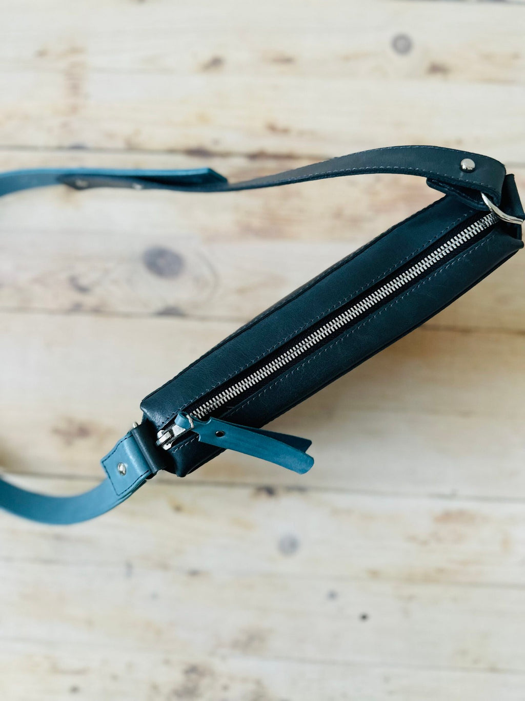 10. Side view of eleriinseim TOURIST crossbody leather bag in Atlantic blue, showcasing zippered closure and slim profile