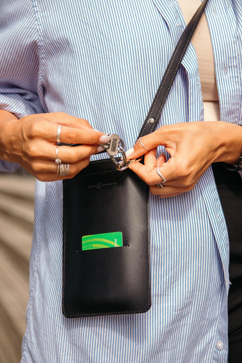 5. Woman holding keys and card with black Stella Soomlais phone bag over blue striped shirt