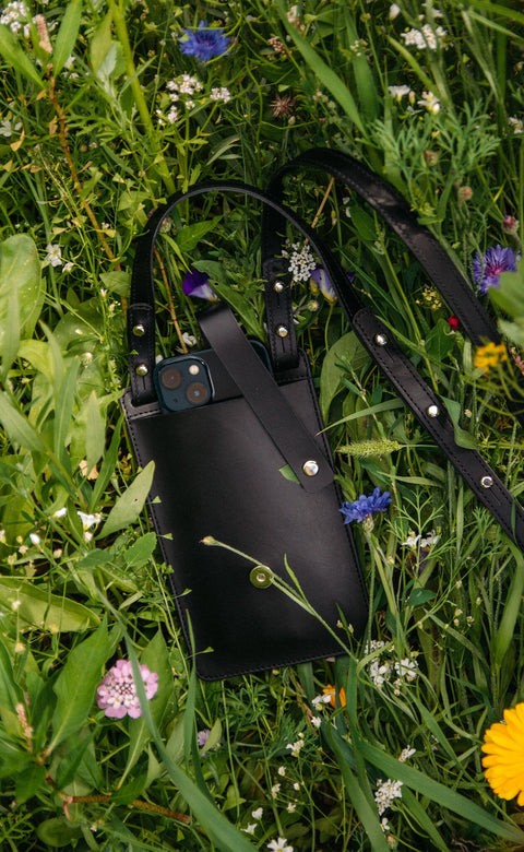 4. Black Stella Soomlais By Your Side phone bag with iPhone 13 Pro in lush green grass